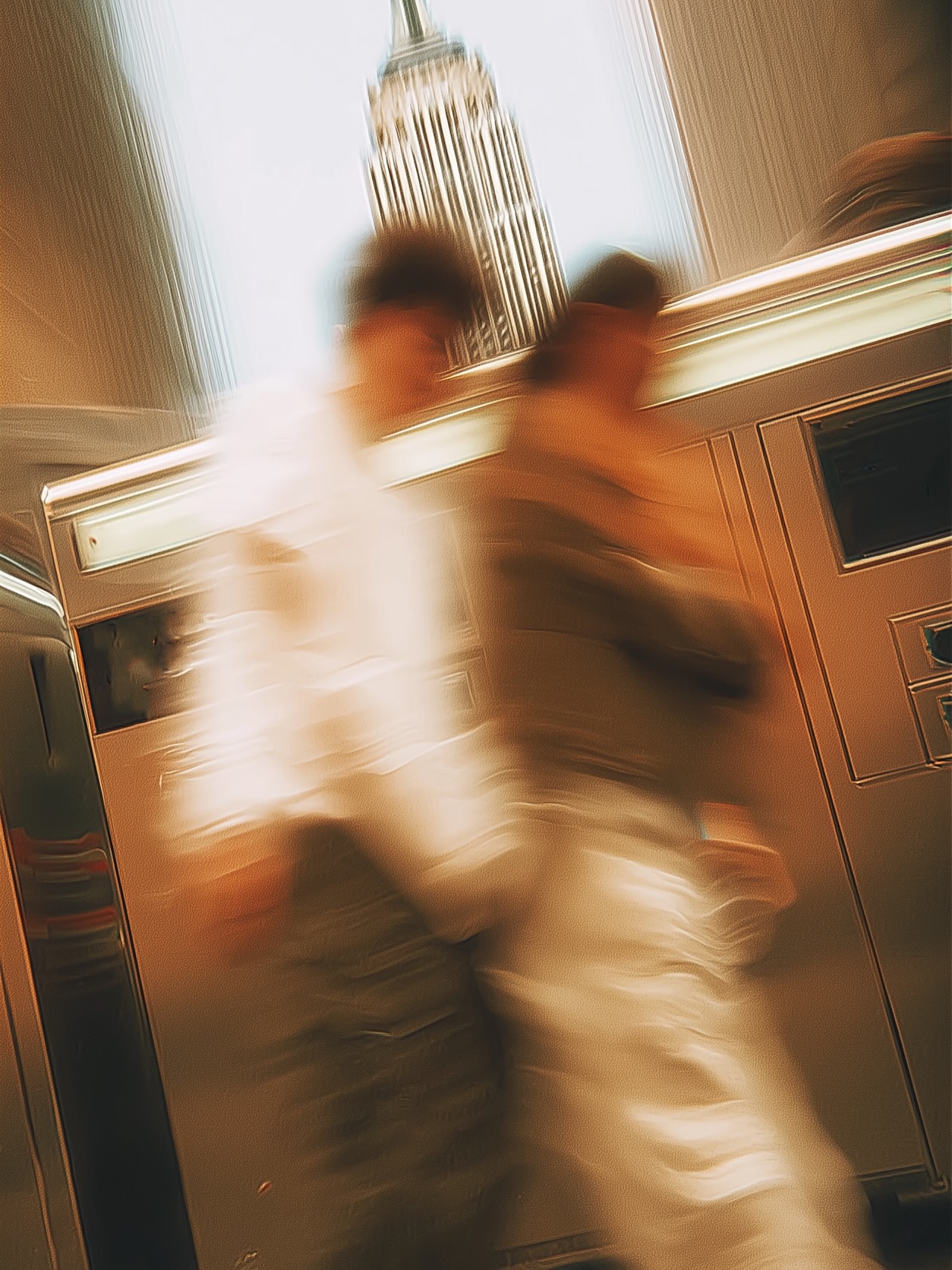Two figures in motion blur crossing a New York street beneath the Empire State Building